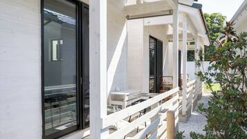 A modern building with large windows, a covered outdoor seating area, and a wooden fence.