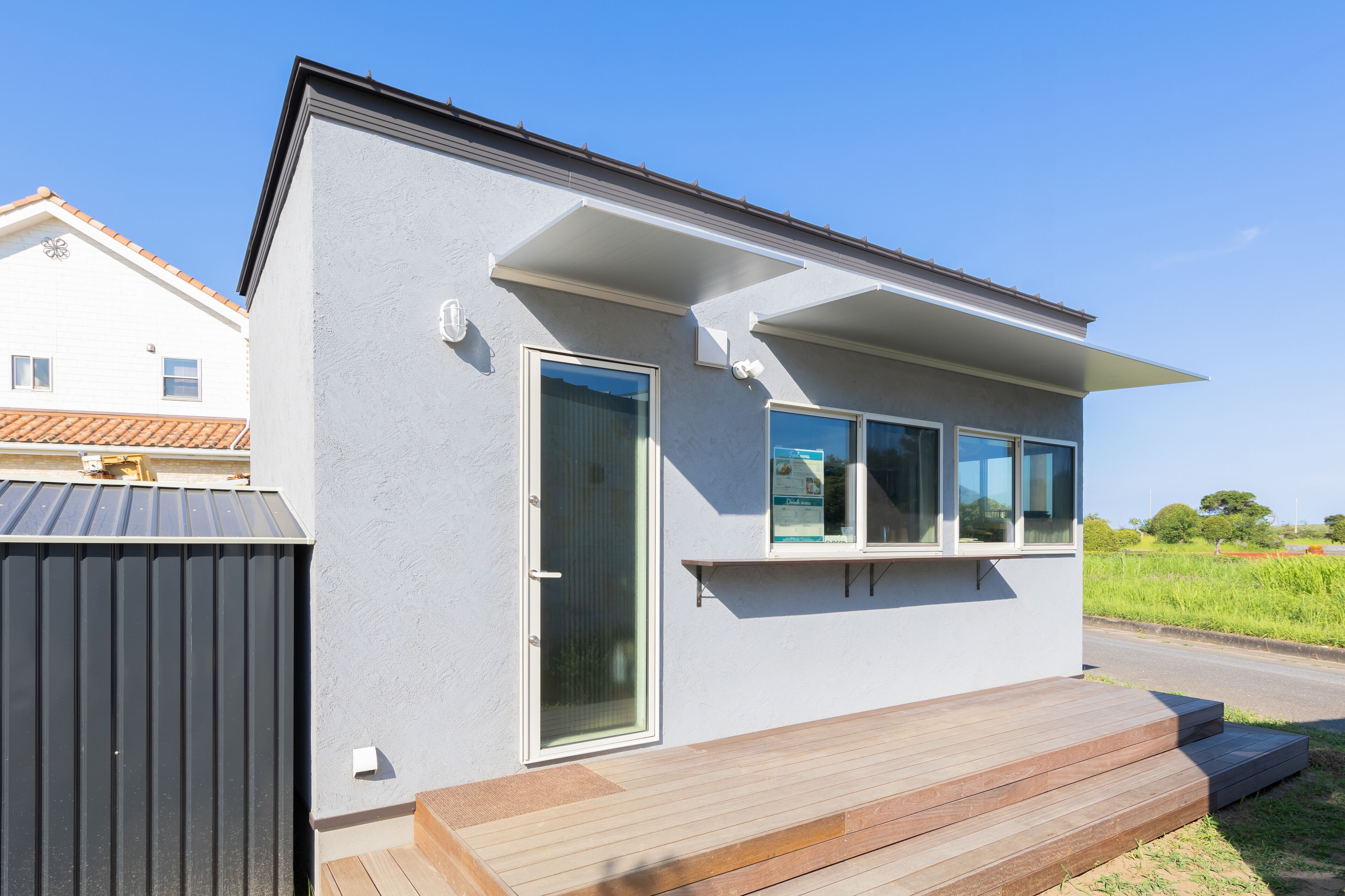 Una moderna casa a un piano con un'ampia porta scorrevole in vetro, un piccolo portico e un tetto in metallo.