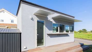 Una moderna casa a un piano con un'ampia porta scorrevole in vetro, un piccolo portico e un tetto in metallo.