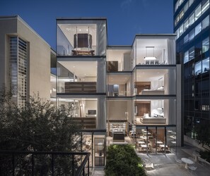 A multi-story building with a glass facade, outdoor seating area, and a visible staircase. - R48 Hotel and Garden (Tel Aviv)