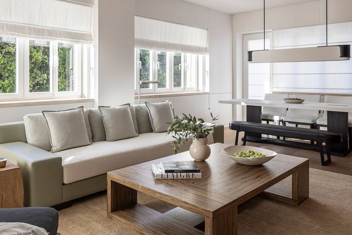 Una sala de estar moderna con un sofá, una mesa de centro y una zona de comedor con un banco y una mesa.