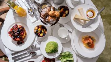 A table set with breakfast items including fruits, pastries, and cheese.
