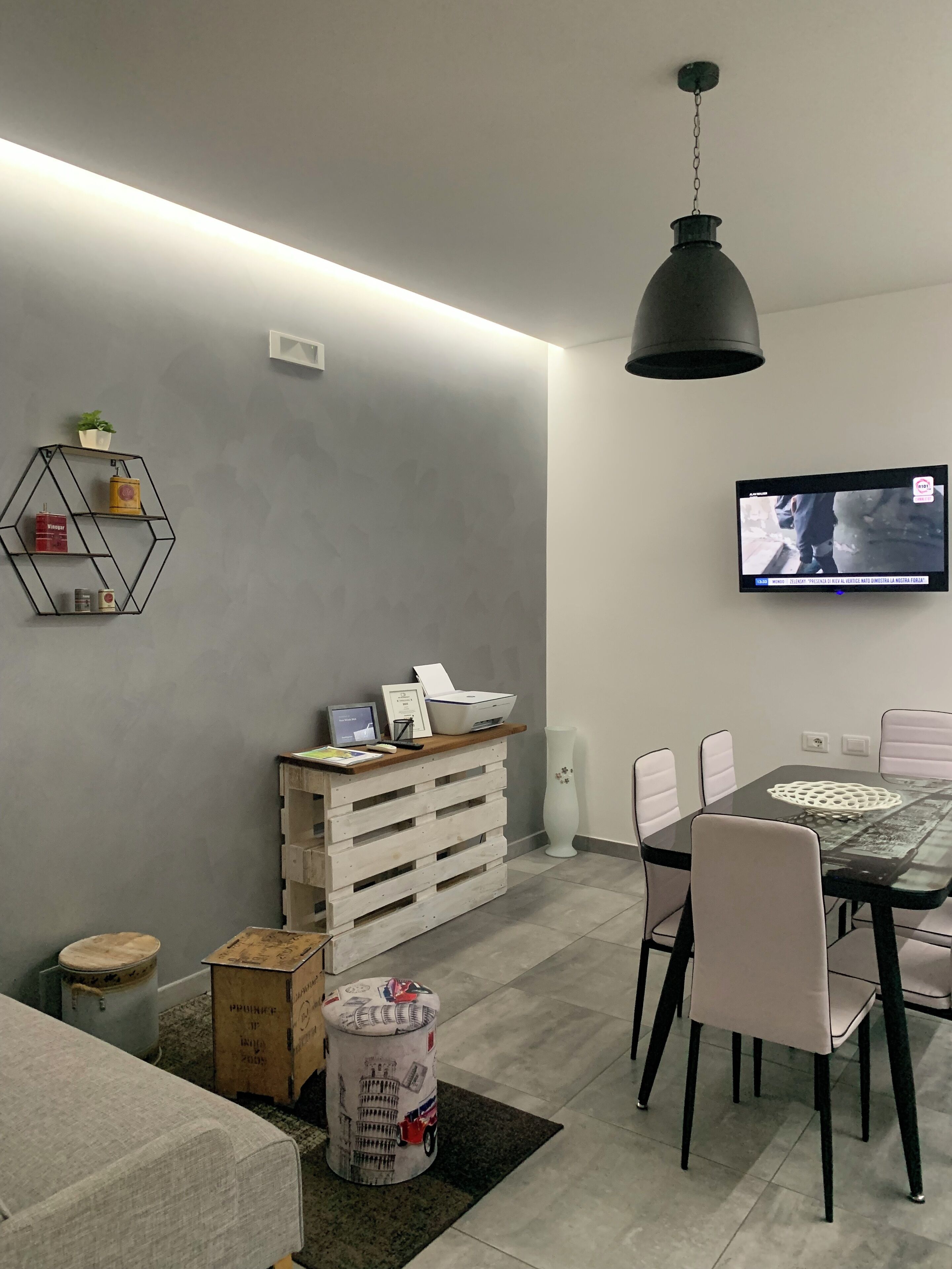 Una sala moderna con comedor, televisor montado en la pared y estantería geométrica.
