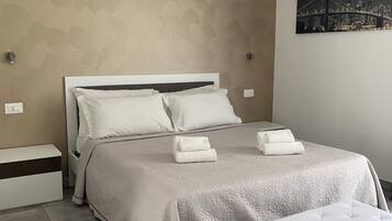 A neatly arranged bedroom with a bed, bedside tables, a bench, and a cityscape artwork on the wall.