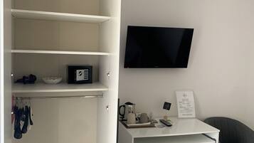 Een moderne, minimalistisch ingerichte kamer met een ingebouwd bureau, een flatscreen-tv en een compacte koelkast.