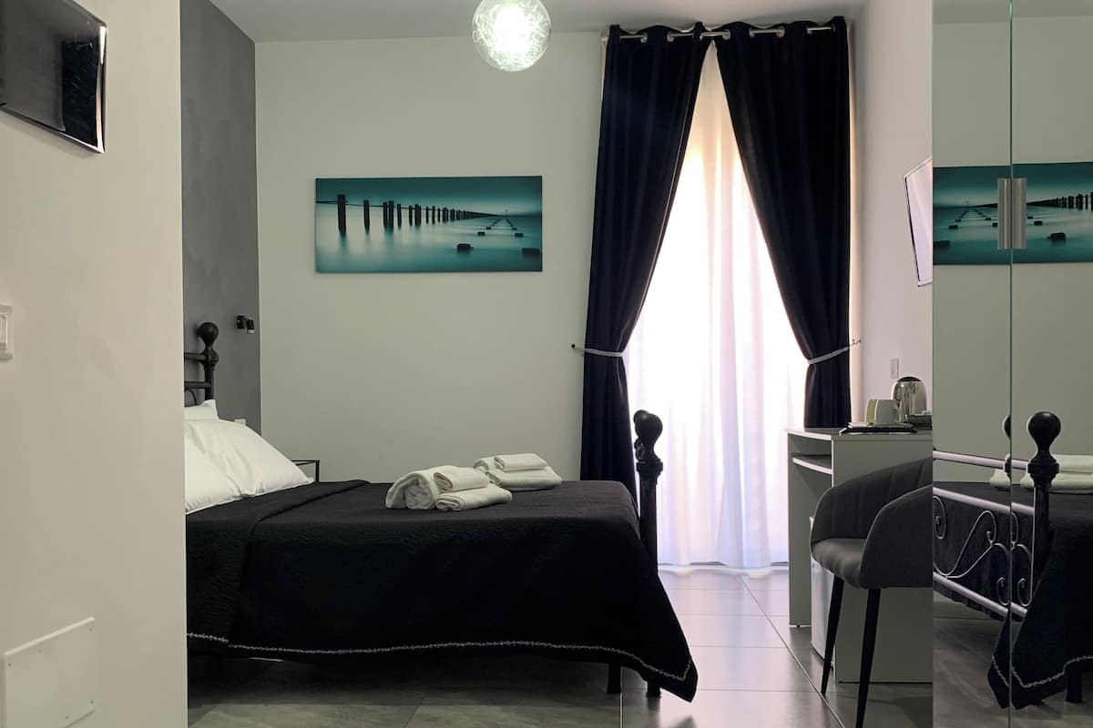 A modern bedroom with a bed, a desk, and a large mirror.