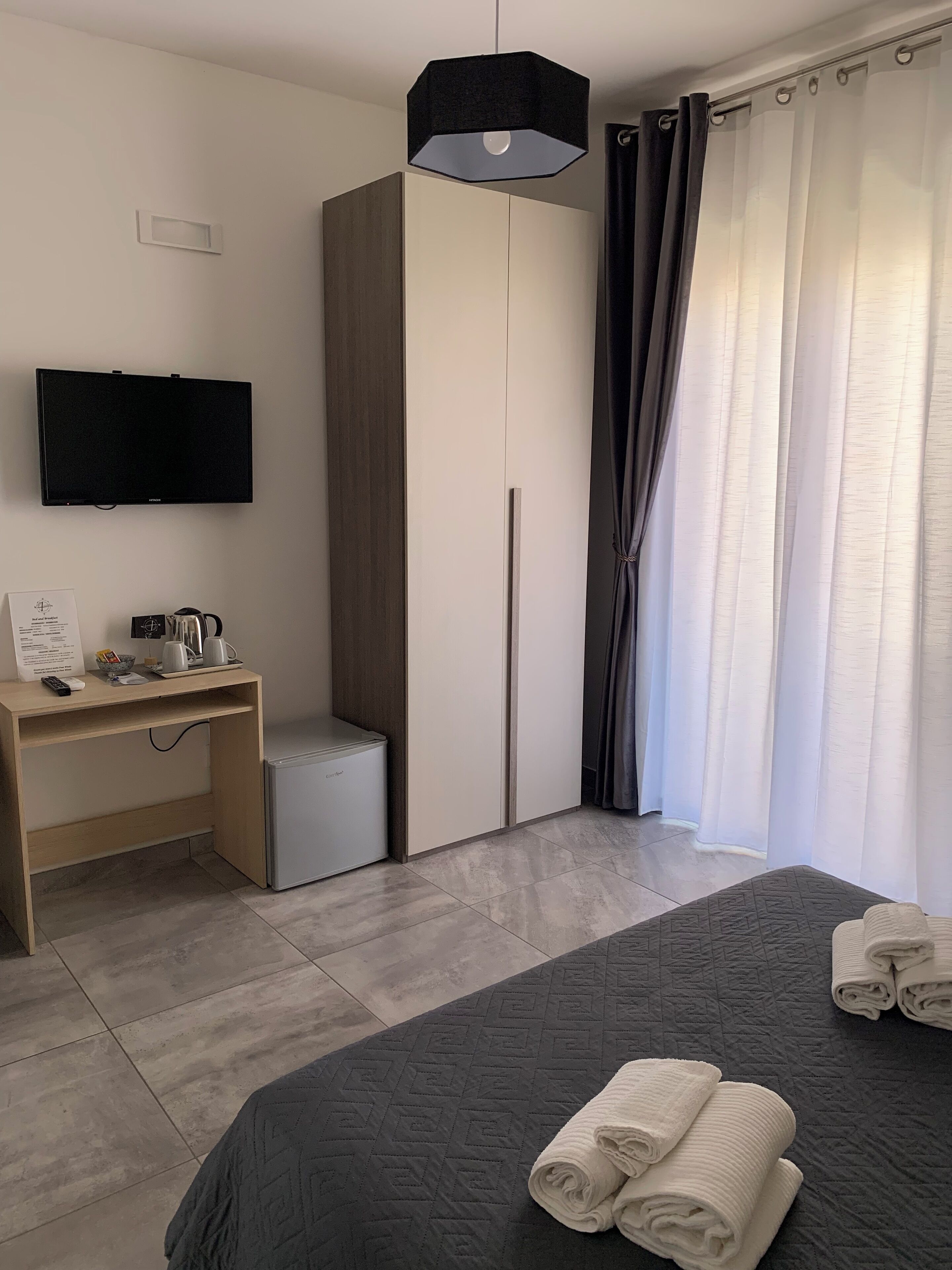 Une chambre d’hôtel moderne équipée d’un lit, d’un bureau avec une machine à café, d’une télévision et d’une armoire.