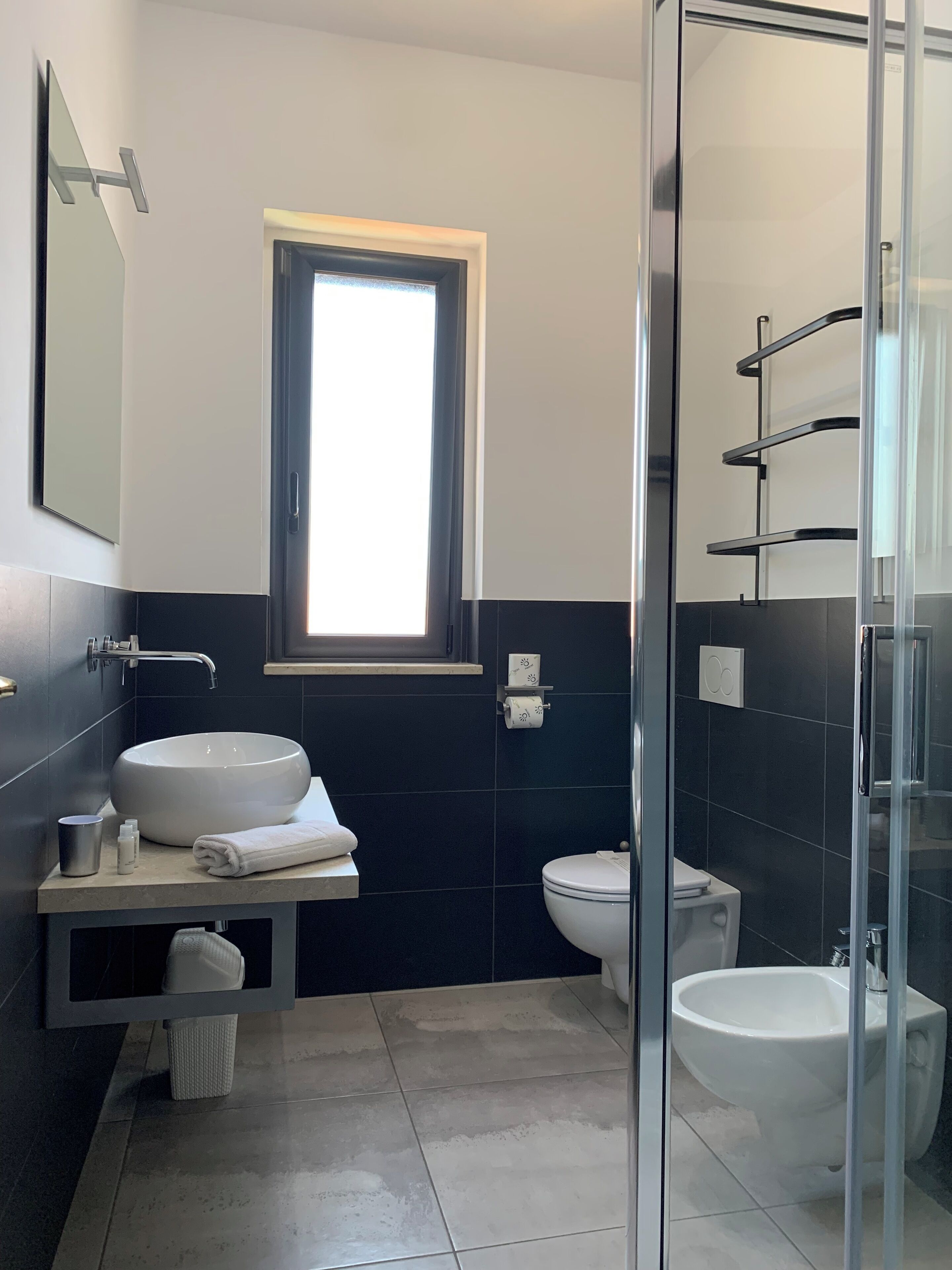 Un baño moderno con un lavamanos grande, un inodoro, un bidé y una ducha con cerramiento de vidrio.