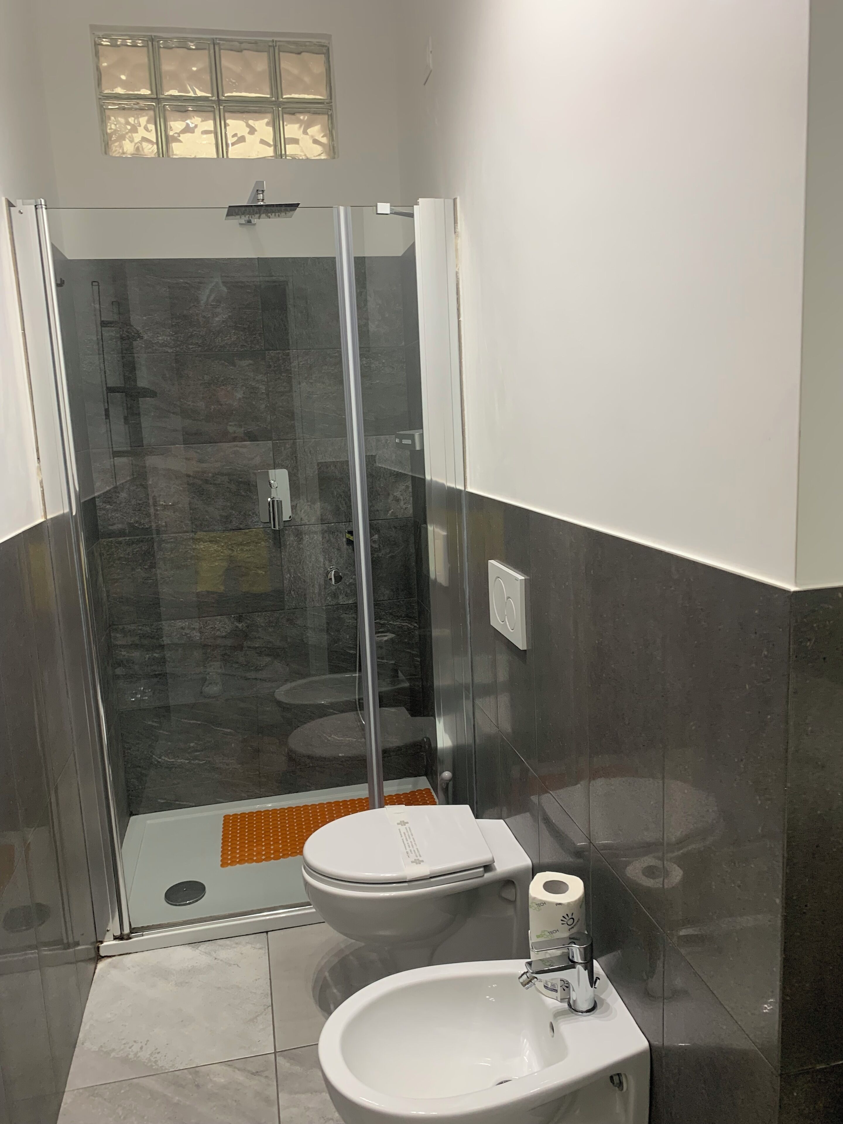 A modern bathroom with a glass-enclosed shower, a white sink, and a toilet.