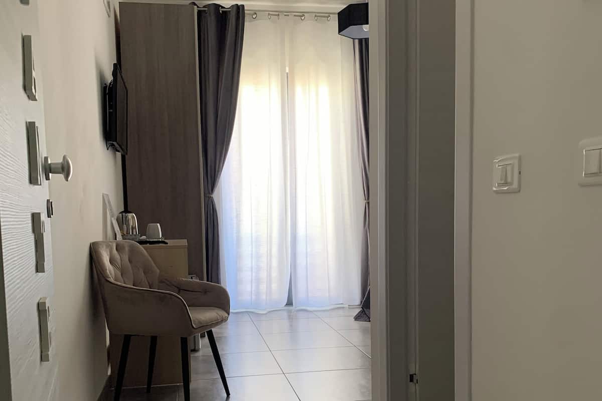 A hallway with a chair, a flat-screen TV mounted on the wall, and a door leading to another room.