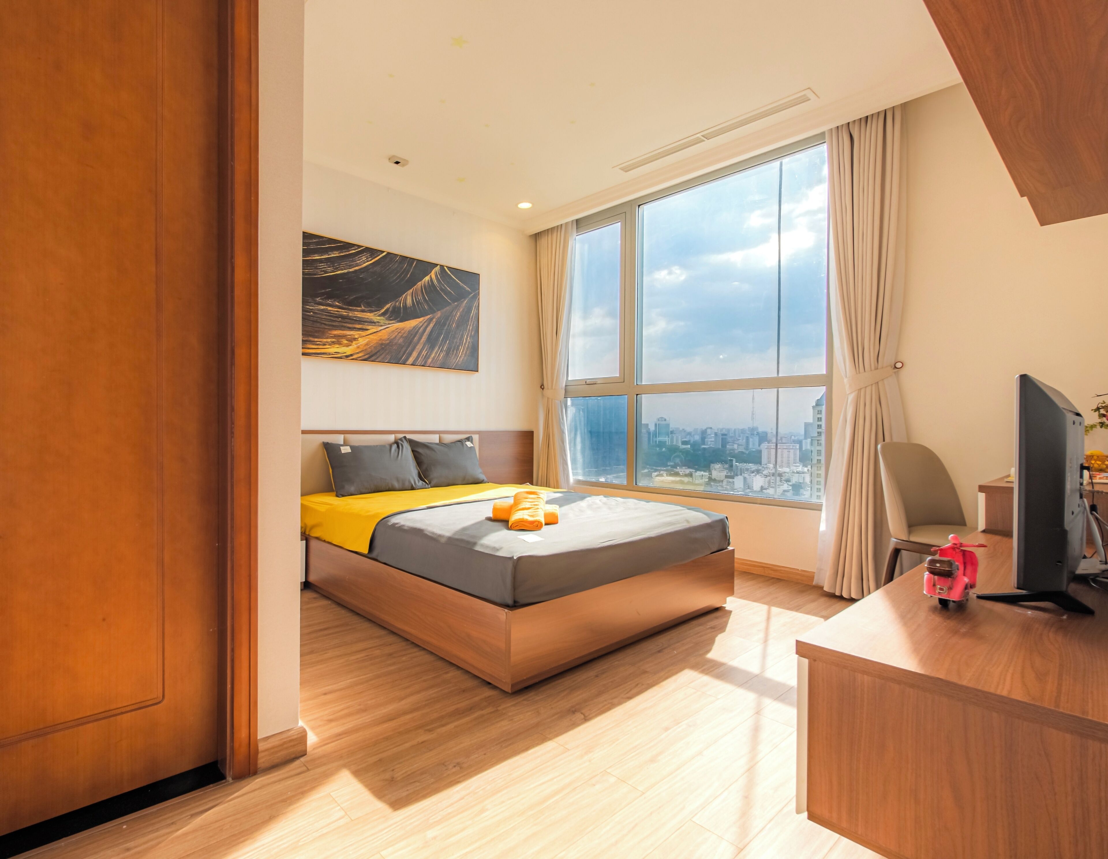 A modern hotel room with a large bed, a desk, and a city view.