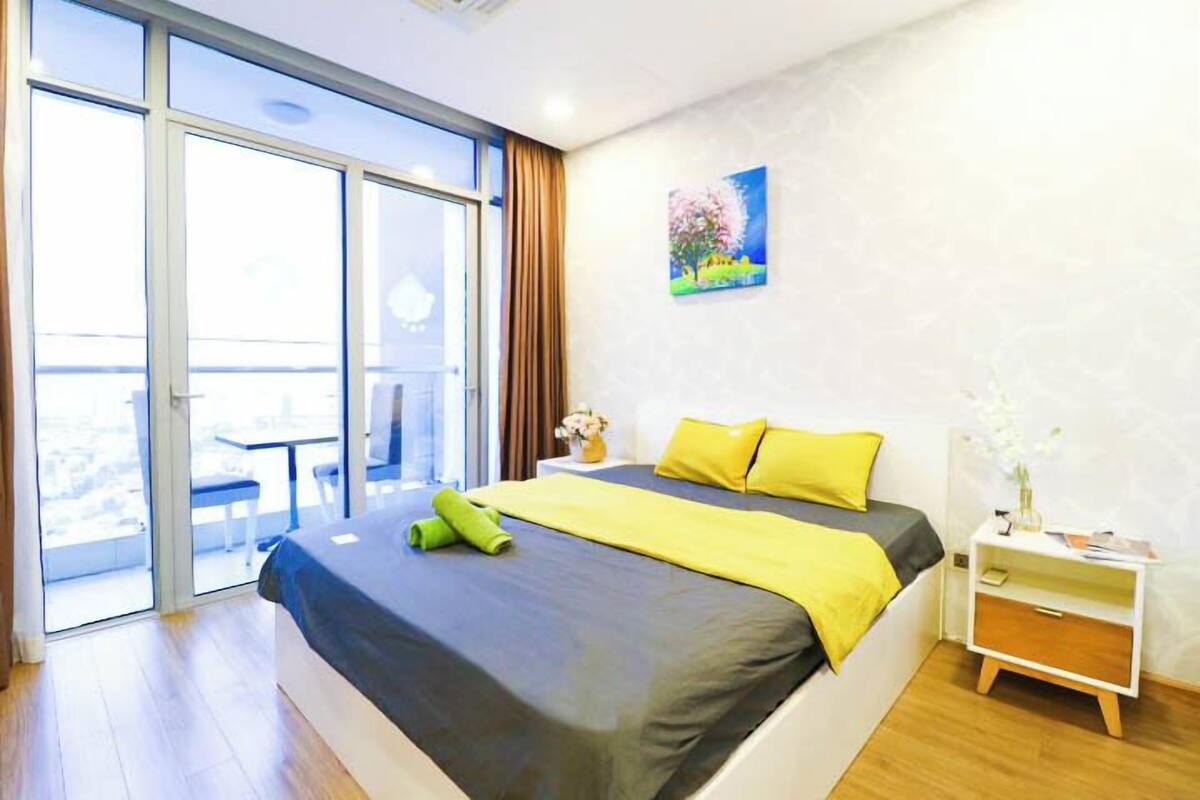 Une chambre à coucher avec un lit, une table de chevet, un tableau et une vue sur l’extérieur, visible à travers une porte coulissante.