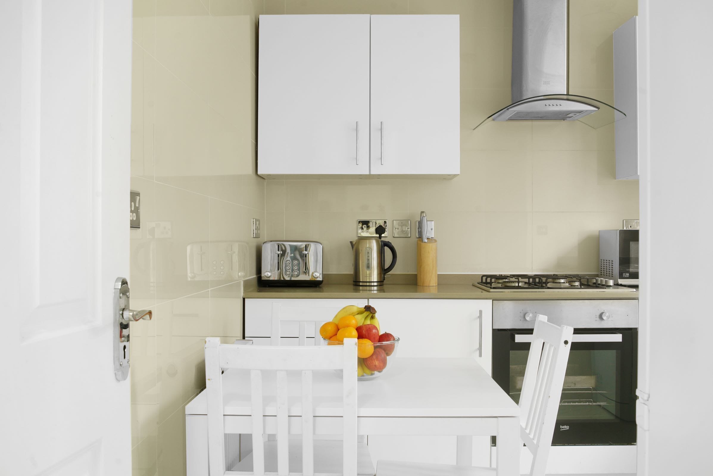 Une cuisine avec des meubles blancs, un grille-pain, une bouilloire, un four à micro-ondes et un four traditionnel.