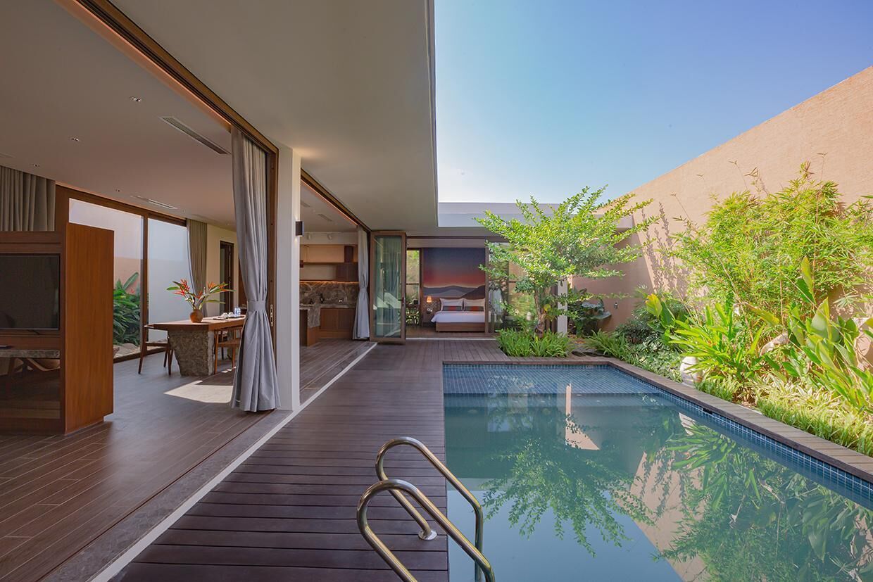 A modern hotel room with a pool, wooden flooring, and a view of the outdoors.