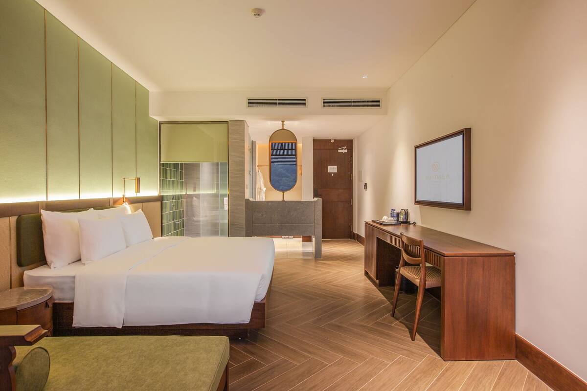 Una habitació d'hotel amb un llit gran, un escriptori, una cadira i una televisió penjada a la paret.