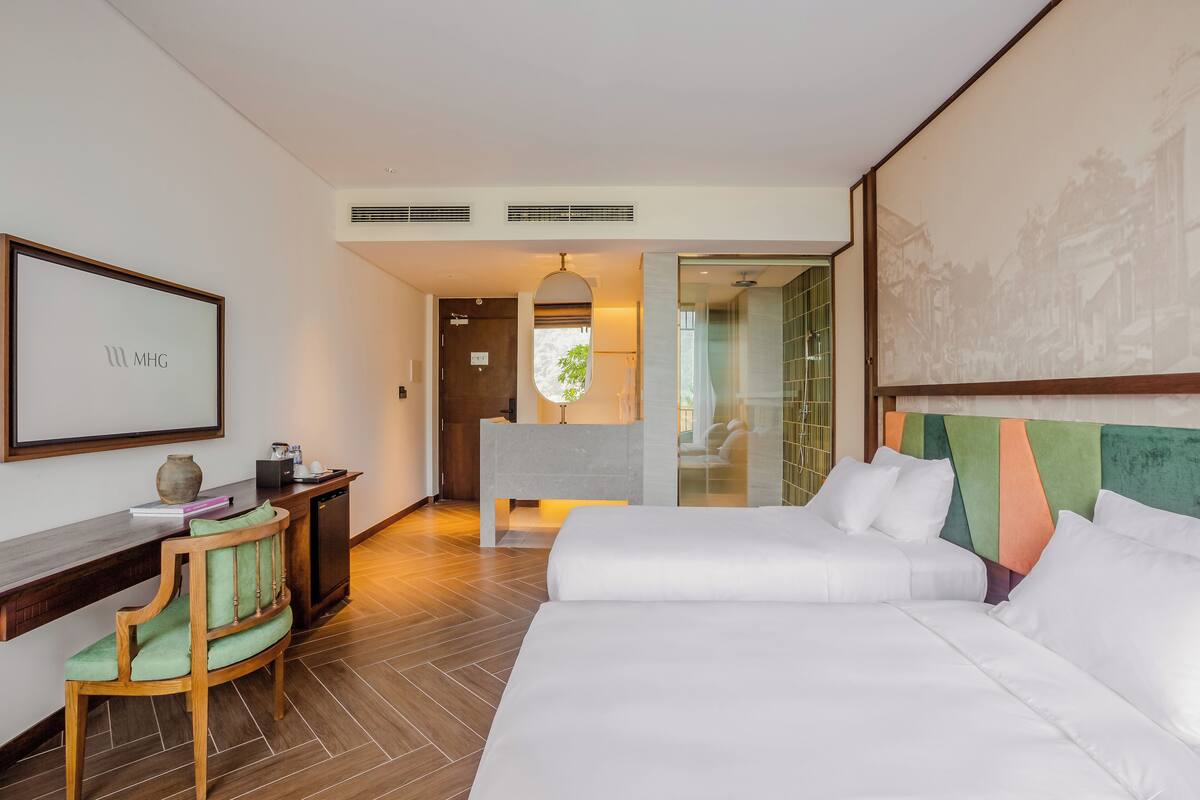 Habitació d'hotel amb llit, escriptori, cadira i un quadre al mur.