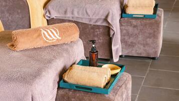 Un área de spa con dos camillas de masaje, cada una con una toalla y dispensador de jabón.