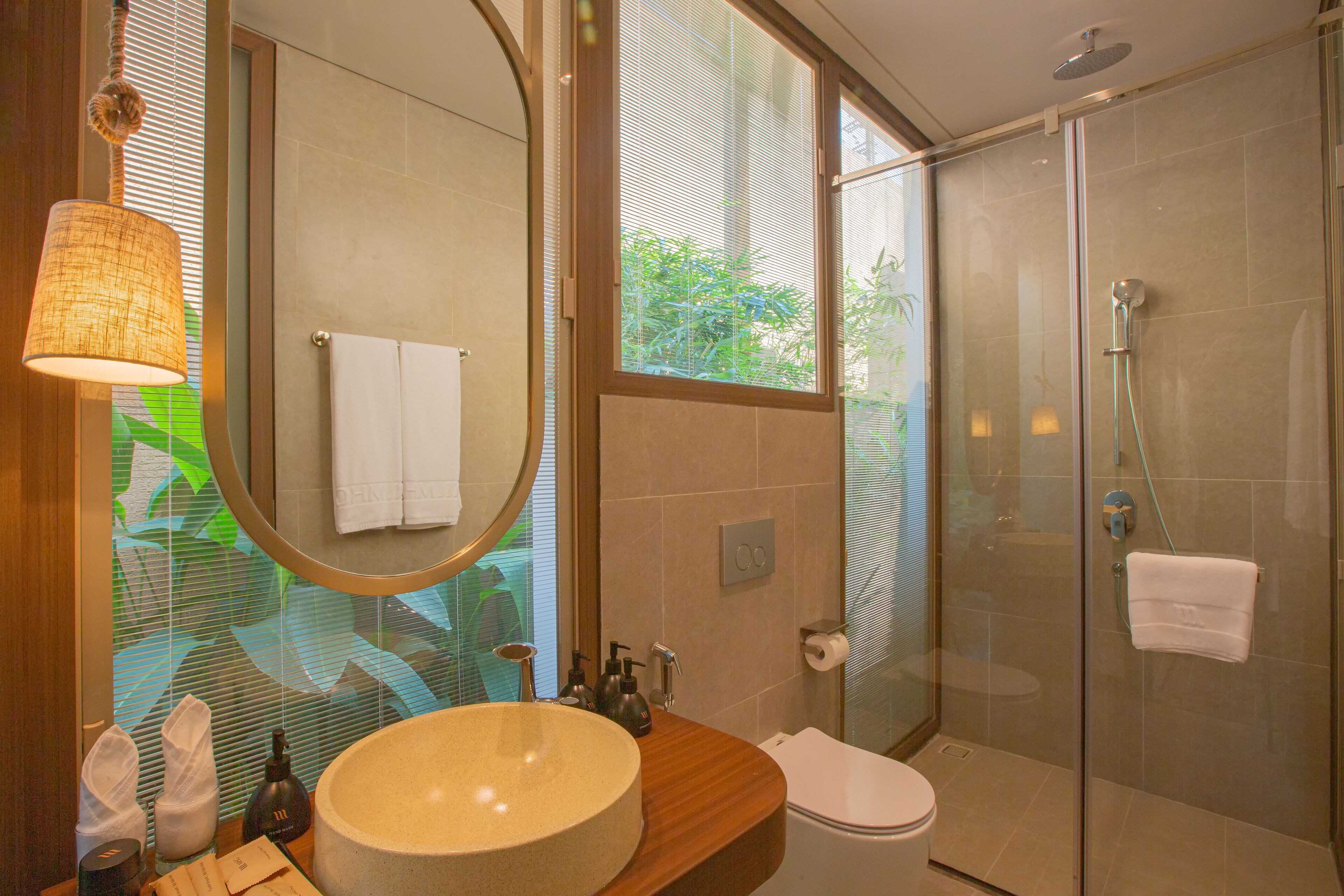 Un baño con lavamanos redondo, inodoro y ducha con cerramiento de vidrio.