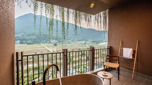 Un balcon avec une baignoire, une chaise et un porte-serviettes.