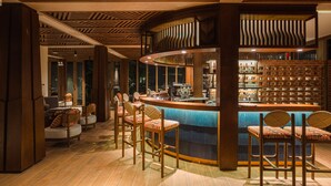 Un espace bar avec des tabourets de bar en bois, un comptoir et un mur en briques.