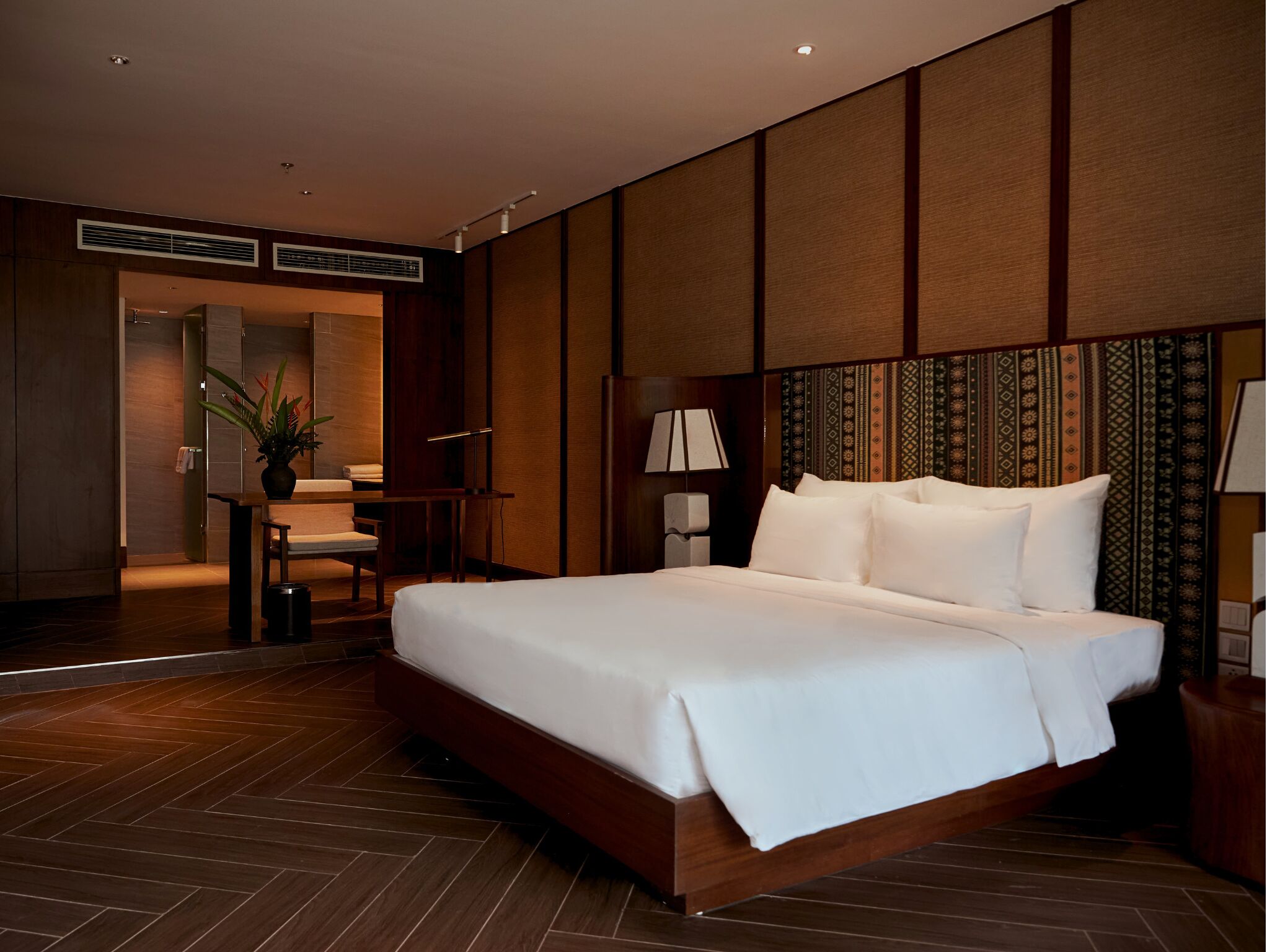 A modern hotel room with a large bed, a desk, and a chair.