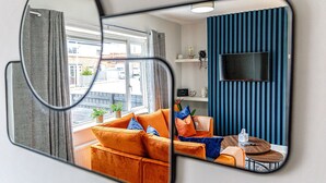 A living room with a sofa, a coffee table, and a TV mounted on a blue wall. - Modern 3 bed, home from home with free parking (Barnsley)