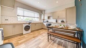 A modern kitchen with a wooden floor, built-in appliances, and a dining area with a bench. - Modern 3 bed, home from home with free parking (Barnsley)