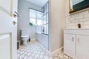 A bathroom with a patterned floor, a toilet, a window with blinds, and a white cabinet. - Modern 3 bed, home from home with free parking (Barnsley)