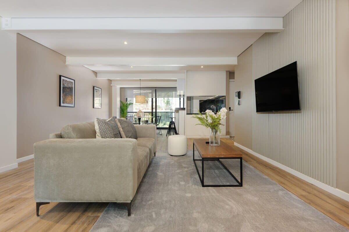 Un salon moderne avec un canapé, une table basse et un téléviseur à écran plat fixé au mur.