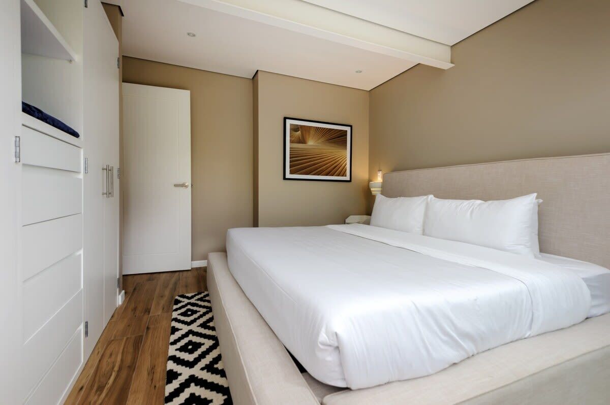 Una habitació d'hotel moderna amb un llit gran, un armari, una porta i un quadre al mur.