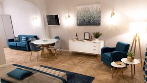 Una sala de estar moderna con comedor, un sofá, una mesa de centro y un cuadro en la pared.