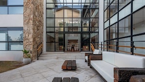 A modern building with a stone facade, large windows, and outdoor seating area with benches and a sofa. - Wanderlust Experience Hotel, BW Signature (Campos do Jordão)