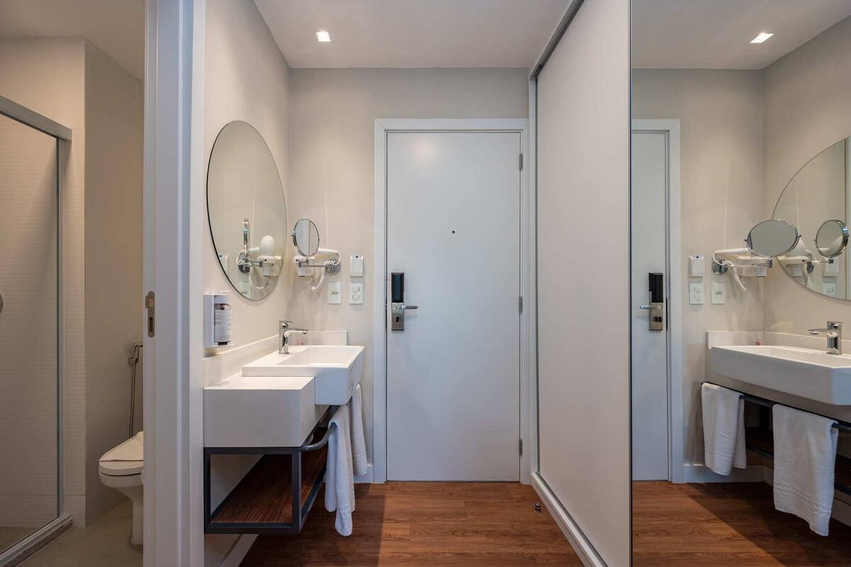 A modern bathroom with two sinks, a toilet, and a door.