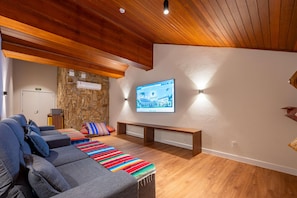 Una sala de estar moderna con una pared de piedra, techo de madera y un televisor de pantalla plana montado en la pared.