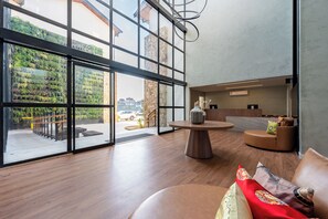 A modern interior with large windows, a wooden floor, a round table, and a seating area with cushions. - Wanderlust Experience Hotel, BW Signature (Campos do Jordão)
