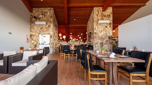 A restaurant with stone walls, wooden ceiling beams, and a variety of seating including sofas and tables. - Wanderlust Experience Hotel, BW Signature (Campos do Jordão)