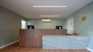 A hotel reception area with a wooden reception desk, marble counter, and a door with a sign. - Wanderlust Experience Hotel, BW Signature (Campos do Jordão)