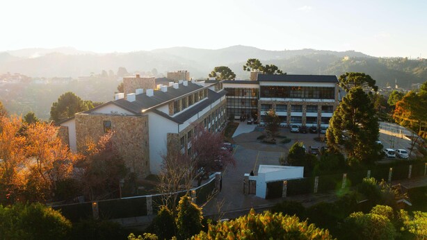 A building with a courtyard, surrounded by trees and hills in the background. - Wanderlust Experience Hotel, BW Signature (Campos do Jordão)