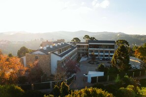 A building with a courtyard, surrounded by trees and hills in the background. - Wanderlust Experience Hotel, BW Signature (Campos do Jordão)