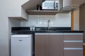 Cocina compacta con microondas integrado, lavamanos y refrigerador.