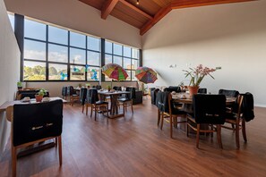 A spacious dining area with large windows, wooden tables, and chairs. - Wanderlust Experience Hotel, BW Signature (Campos do Jordão)