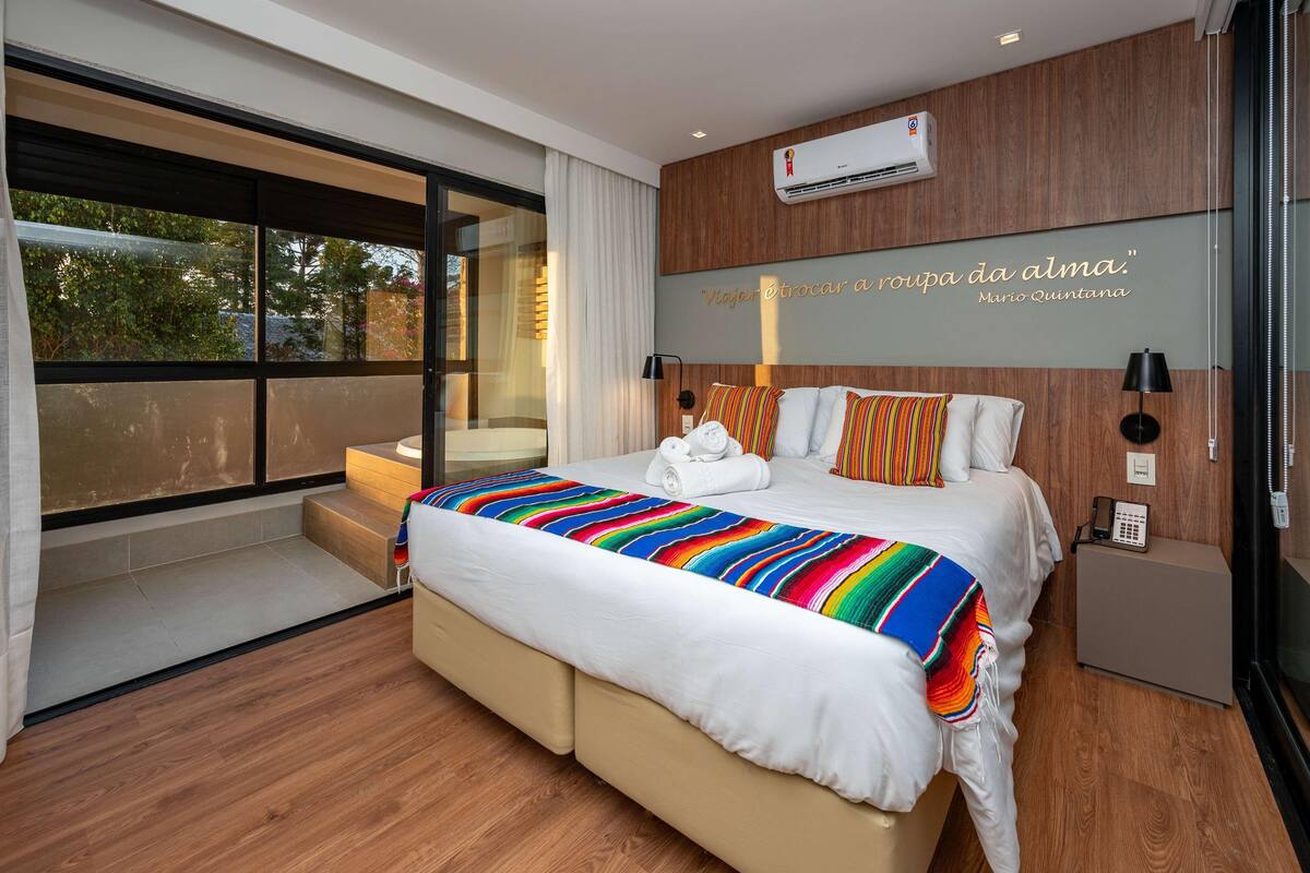 A modern hotel room with a large bed, a bedside telephone, and a wall-mounted air conditioner.