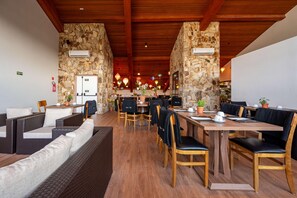 A restaurant with stone walls, wooden ceiling beams, and a variety of seating including sofas and tables. - Wanderlust Experience Hotel, BW Signature (Campos do Jordão)