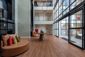 Un vestíbulo amplio con una mesa redonda de madera, asientos de cuero y grandes ventanales que ofrecen vistas al exterior.