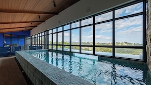 A long indoor swimming pool with a view of the landscape through large windows. - Wanderlust Experience Hotel, BW Signature (Campos do Jordão)