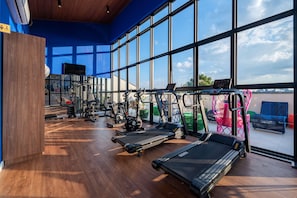 Un gimnasio con cintas de correr, bicicletas estáticas y máquinas de pesas.