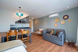 A modern living room with a grey sofa, wooden dining table, and chairs. - Wanderlust Experience Hotel, BW Signature (Campos do Jordão)