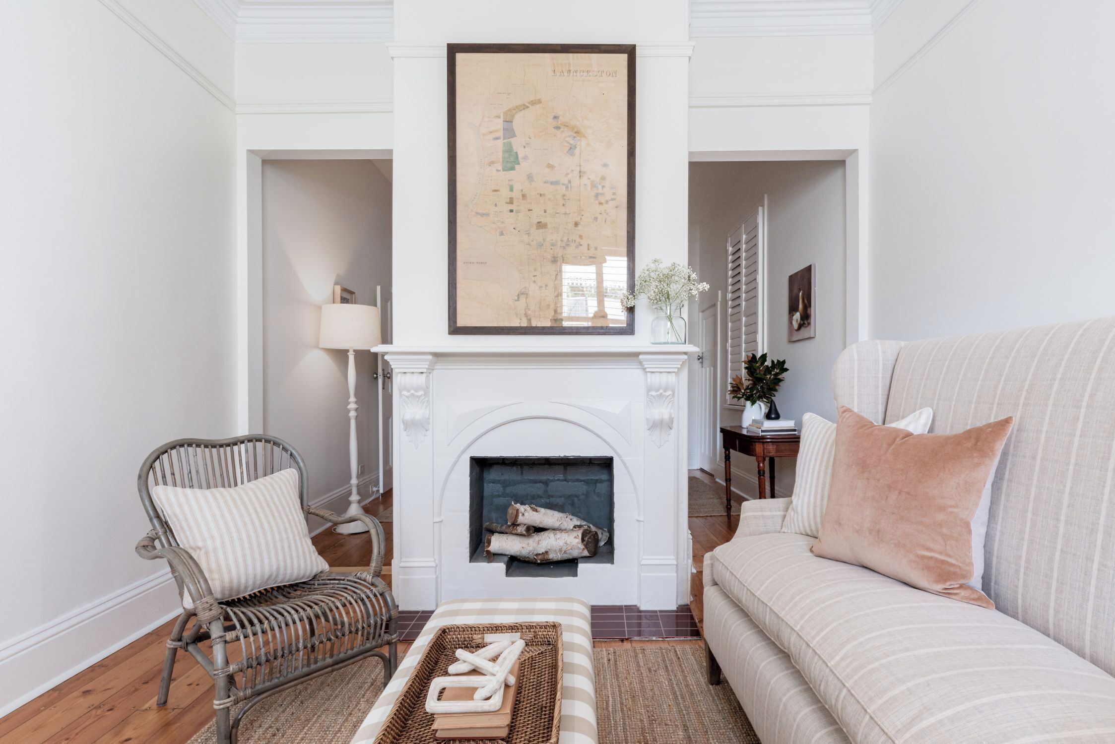 A living room with a fireplace, a map on the wall, a sofa, a chair, and a coffee table.