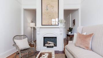 A living room with a fireplace, a map on the wall, a sofa, a chair, and a coffee table.