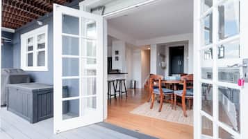 An open door leading to a dining area with a wooden table and chairs, a grill outside, and a view of the interior.